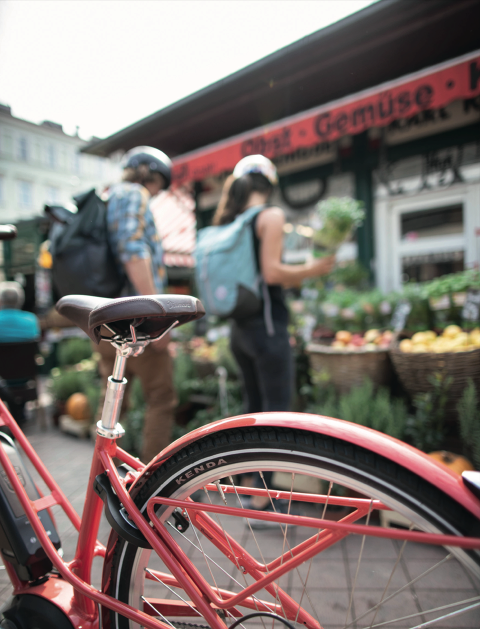 Pink bicycle with Kenda Kwick tire and a blurred background of a market scene